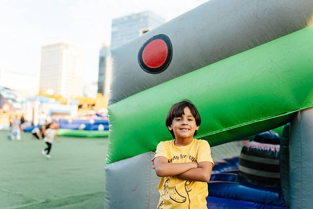 Young boy posing at the camera in front on an inflatable slide