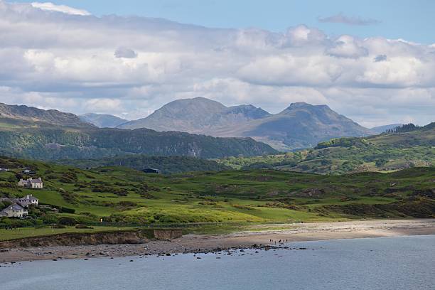 istock Rolling green hills meet a calm sea under a partly cloudy sky. 2215952175
