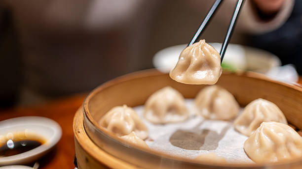 istock Taiwanese person picking xiaolongbao dumpling with chopsticks at restaurant 2215952315