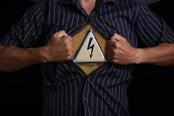 Image with a warning sign. Man rips open his shirt, exposing high voltage sign that symbolizes danger or inner strength