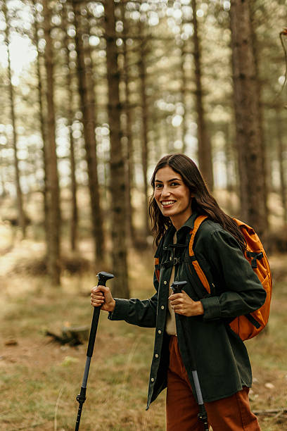 istock Young female hiker exploring forest trail with backpack and trekking poles 2215955556