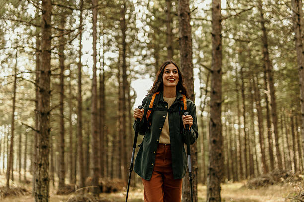 istock Young female hiker explores forest trail with trekking poles and backpack 2215955651