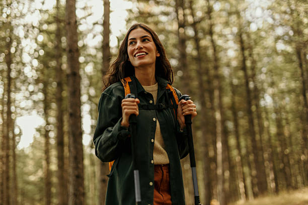 istock Young female hiker exploring a forest trail with trekking poles and backpack 2215955652