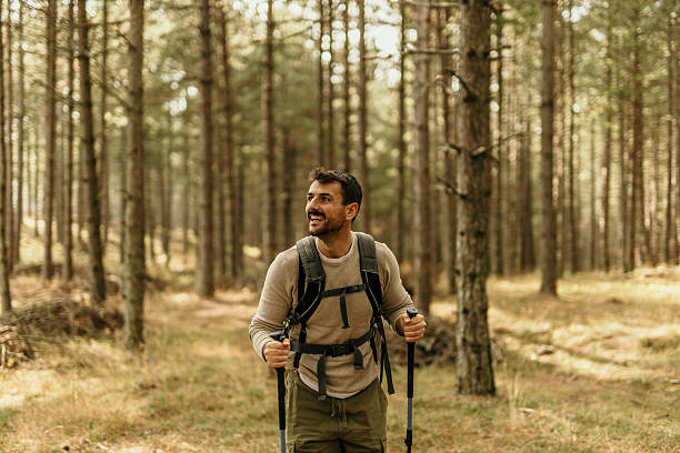 istock Smiling hiker exploring forest trail with backpack and trekking poles 2215955667