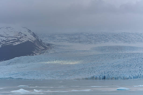 istock Glacier lagoon reflecting cloudy sky with floating icebergs 2215956851