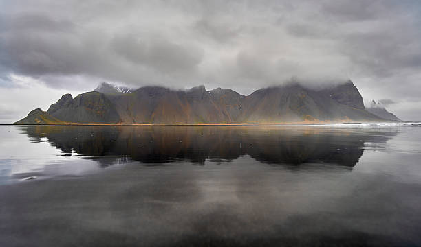 istock Calm water reflecting dramatic Vestrahorn mountain range under cloudy sky 2215956901