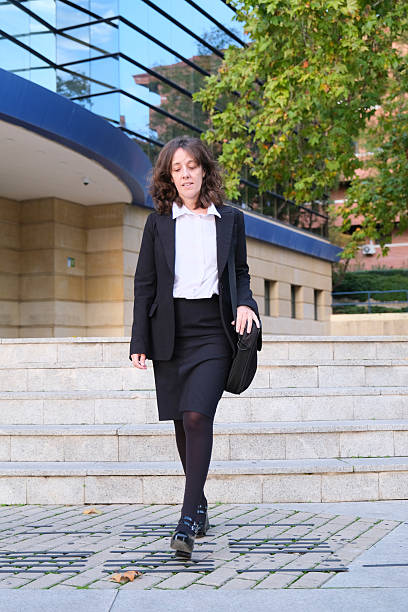 istock Executive woman walking down stairs leaving office building 2215962982