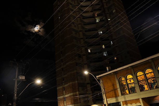 Night scene in Brazil with illuminated church against a tall building. Moon adds drama, tangled wires create an interesting pattern.