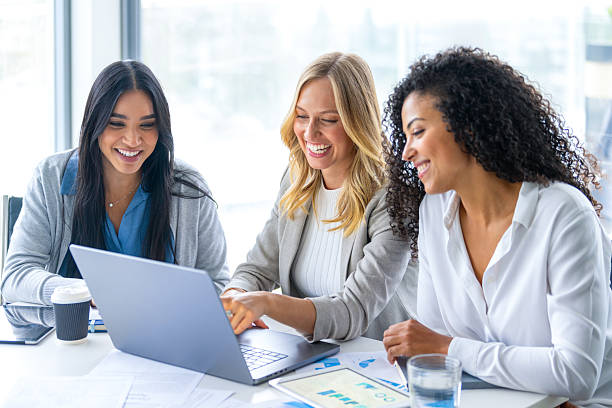 istock Three women meeting in a board room. There is a laptop computer on the table along with paperwork showing financial data charts and graphs. 2215971532