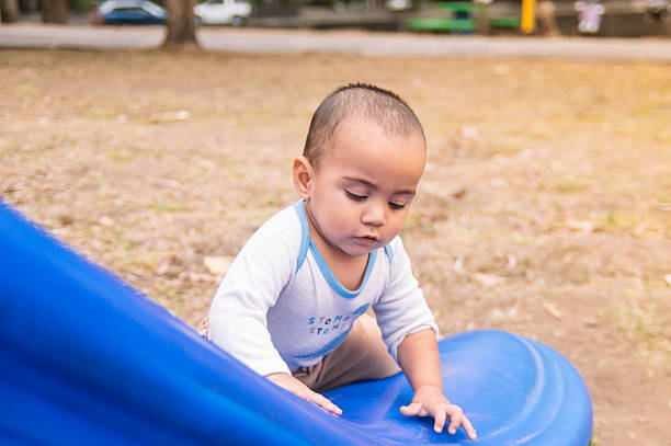 Hispanic toddler climbing blue slide in park