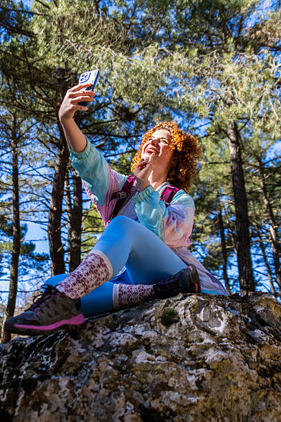 istock Young hiker taking a selfie while resting on a rock in the forest 2215972309