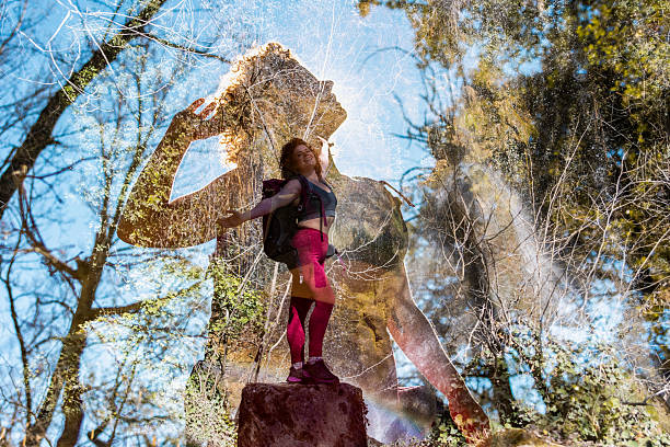Young hiker standing on a rock with double exposure effect in the forest, enjoying the sunlight