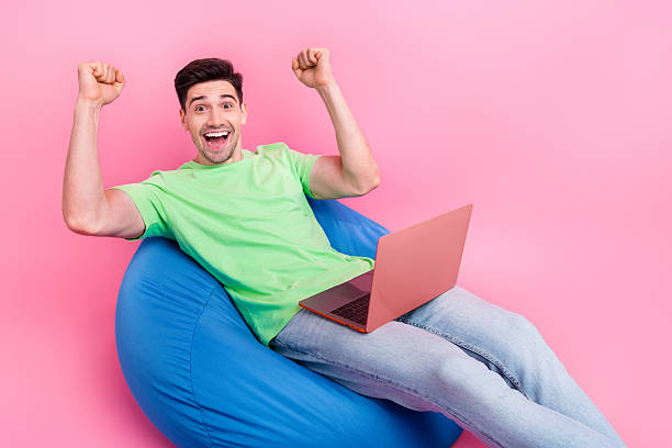 istock Photo of young man professional programmer raised fists up achieved final results using laptop isolated over pink color background 2215976955