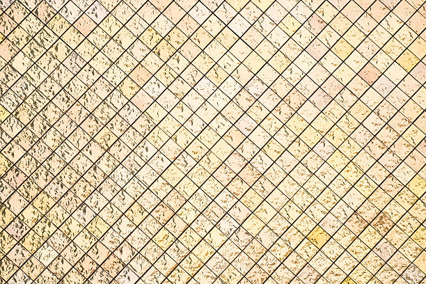 Close up of a gold mosaic tile wall with reflective surfaces and geometric square patterns. Ideal for backgrounds, textures, or architectural design concepts.