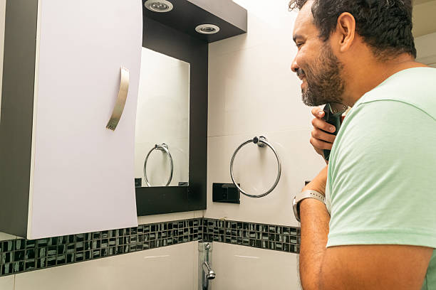 A brush with a wooden handle and a gray razor on a gray background. The concept of facial hygiene.