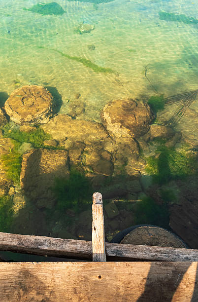 istock Wooden Dock with Anchor and Rope on Turquoise Lake 2215978721