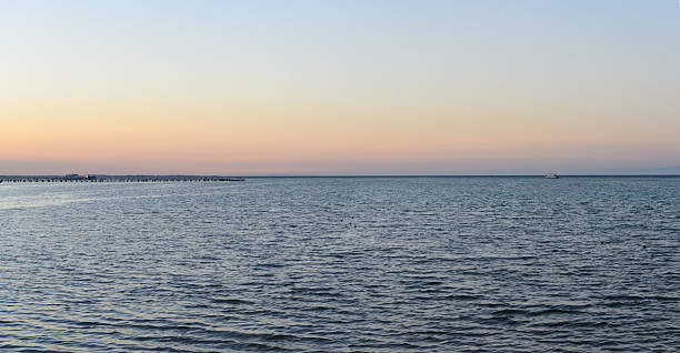Serene seascape at dawn with a soft gradient sky, calm water, and distant pier. Evokes peace, tranquility, and a sense of freedom. Ideal for travel, wellness, or inspirational themes.