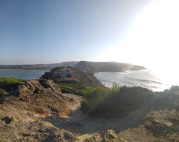 istock Scenic coastal landscape featuring a rocky path leading towards a distant headland. Bright sunlight creates a sense of adventure and exploration. Ideal for travel, nature, or adventure themes. 2215982321