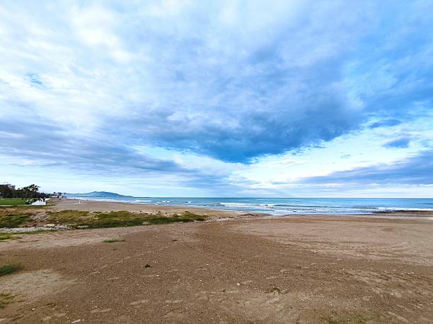 Serene beach scene with dramatic clouds, soft light, and a sense of tranquility. Perfect for travel, nature, or introspective themes. Evokes peace and escape.