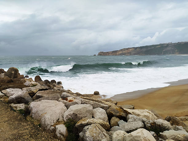 istock Dramatic seascape featuring powerful waves crashing against a rocky shore under a stormy sky. Evokes themes of resilience, natures power, and coastal beauty. 2215982365