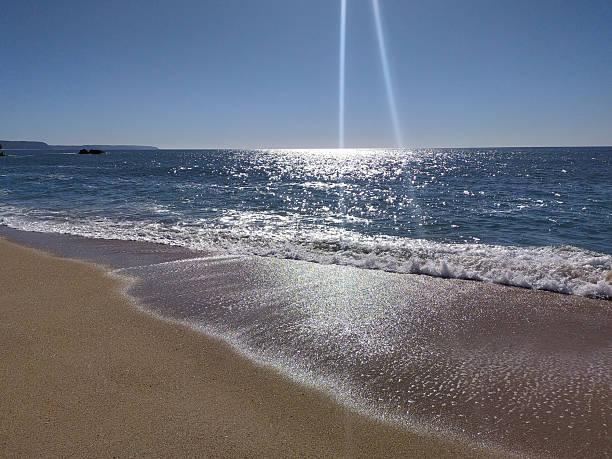istock Serene ocean view with sparkling sunlight reflecting on the waters surface, meeting the sandy shore. Represents peace, vacation, or summer getaway. 2215982407