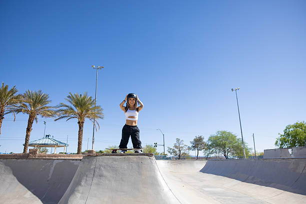 A female littler person skateboarding at the skate park.
