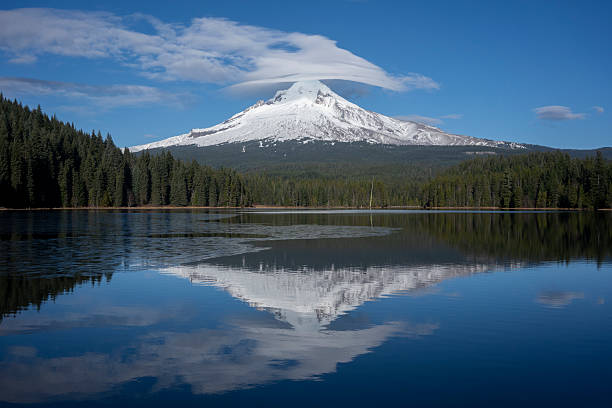 Lenticular clouds in formation over snow-covered Mount Hood on a sunny winter day viewed from the Trillium Lake.
