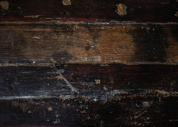 Close-up shot of a distressed, dark wooden surface with visible scratches, deep grain, and signs of weathering and age.\nConcept: dark wood texture, distressed wood background, grunge wood, vintage timber, rustic surface, old wooden board, aged material texture, weathered wood panel, antique wood grain, moody background