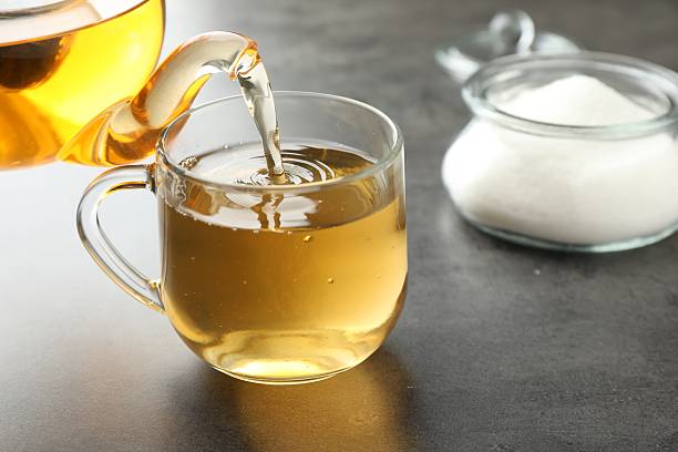 istock Pouring tasty tea into cup at grey table indoors, closeup 2215997065