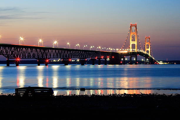 istock Suspension bridge glowing over calm water at twilight 2216002904