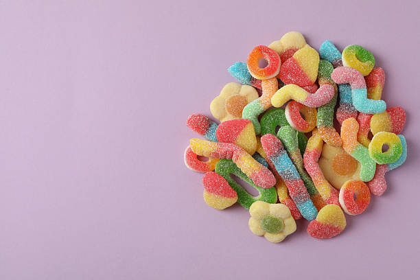 Gummy candies on violet background, space for text