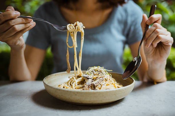 Asian woman enjoy eating a testy spaghetti carbonara  in Italian restaurant.