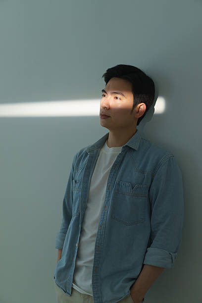 istock Contemplative Man in Denim Shirt with Sunlight through Window 2216013940