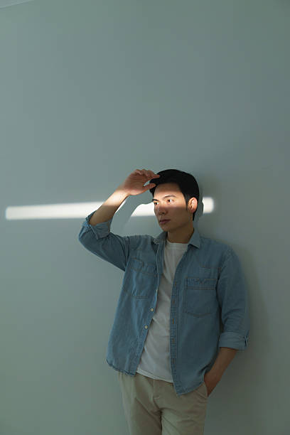 Man Standing Near Wall with Subtle Sunlight Beam