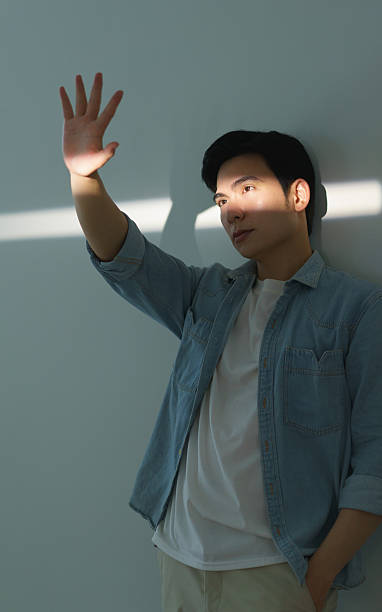 istock Young Man Posing Dramatically Against a Minimalist Background with Sunlight Shade 2216013946