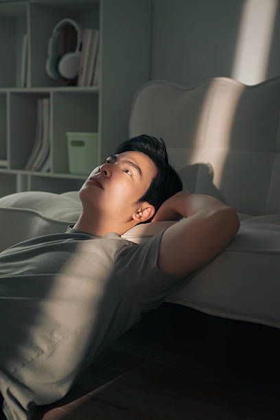 istock Relaxed Man Reflecting Near a Sunlit Couch at Home 2216013985
