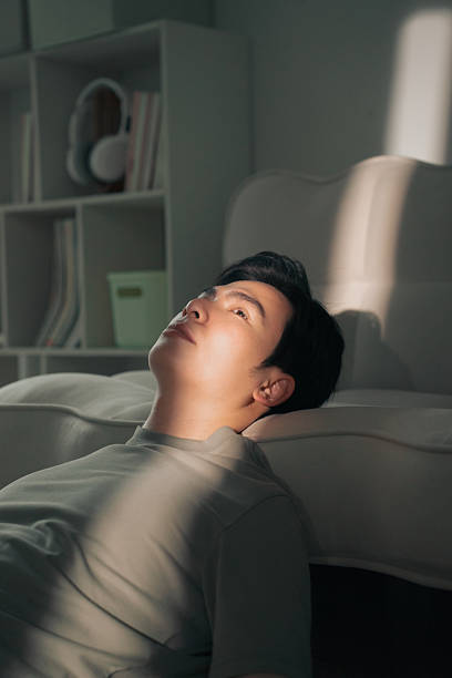istock Young Man Lying on The Floor in Sunlight, Looking Pensive and Relaxed 2216013986