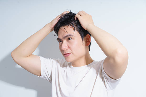 istock Young Man Grooming Hair in Bright Lighting with Relaxed Expression 2216014043