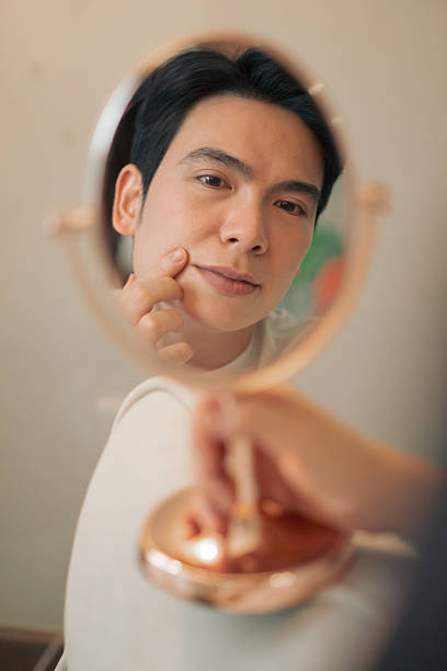 Man Examining His Face in a Handheld Mirror at Home
