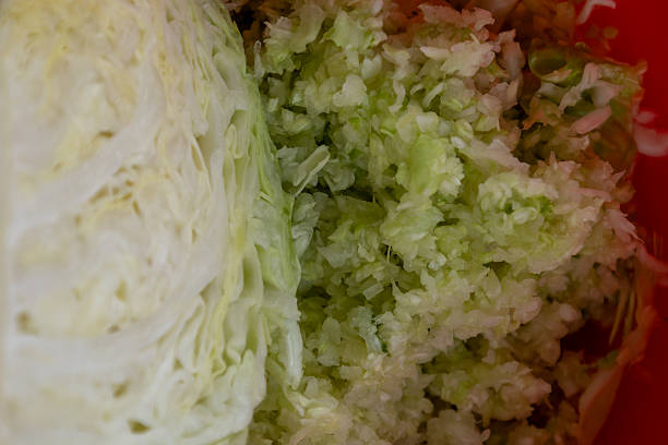Close-up view of shredded cabbage alongside a fresh quarter cabbage. Ideal for healthy food content, cooking tutorials, or farm-to-table visuals.