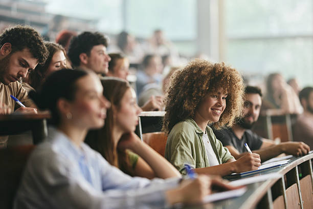 istock Happy female student taking notes on a class in amphitheater. 2216018575