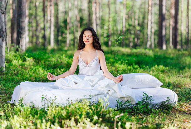 istock Young woman is sitting in the forest on a white bed 2216020793