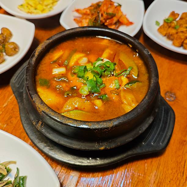 istock Korean Army Stew Budae Jjigae with Side Dishes on Wooden Table 2216020921