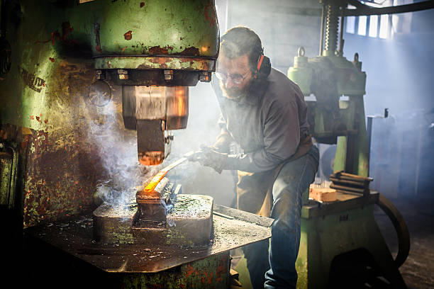 istock Mid Adult Male Blacksmith Shaping Hot Metal Under Bright Workshop Lighting 2216021402