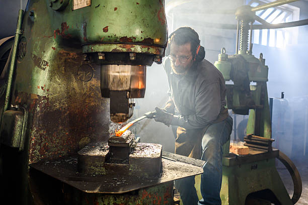 istock Mid Adult Male Blacksmith Working Indoors with Hydraulic Press in Rustic Workshop 2216021403