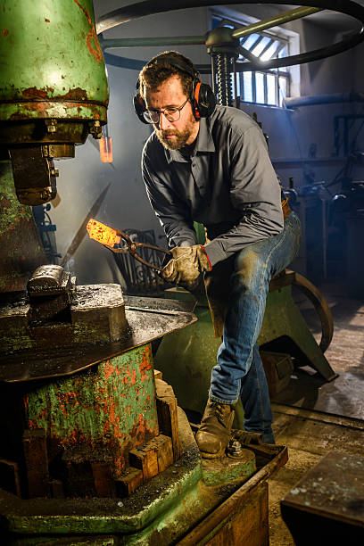 istock Skilled Blacksmith Operating Industrial Hydraulic Press In Traditional Workshop 2216021412