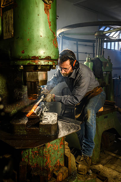 istock Focused Blacksmith Shaping Glowing Metal with Hydraulic Press in Industrial Workshop 2216021418
