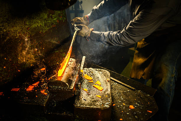 A mid-adult blacksmith of Caucasian ethnicity works skillfully in a dim workshop, shaping glowing, molten metal using a hydraulic press. Protective gloves and apron enhance safety in this traditional metalworking craft.