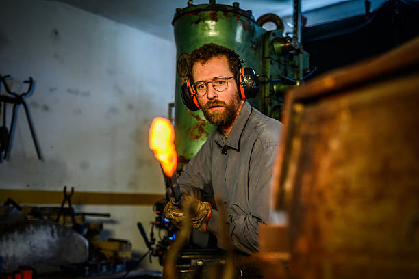 istock Mid-Adult Blacksmith Working With Glowing Metal In Traditional Forge Workshop Under Dramatic Lighting 2216021446