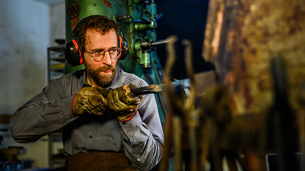istock Focused Male Blacksmith in Protective Gear Heating Metal in Forge Under Bright Workshop Lighting 2216021467